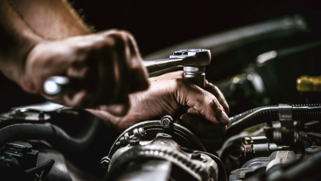 mechanic hands working on an engine with tools